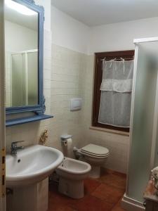 une salle de bain avec un lavabo, des toilettes et un miroir dans l'établissement Borgo Acque Romane, à Servigliano 20 autres photos