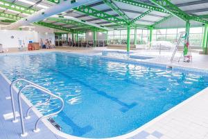 a large swimming pool with blue water in a building at Lyndean - Skipsea Sands in Skipsea