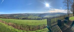 a fence in a field with the sun in the sky at Gîte " Le Normand " Sa Vue Splendide in Vimoutiers +31 photos