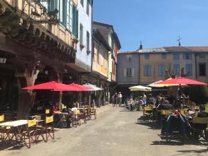 a group of people sitting at tables under red umbrellas at Malepère in La Bastide-de-Bousignac