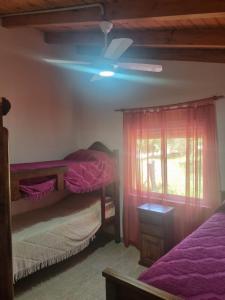 ein Schlafzimmer mit zwei Betten und einem Deckenventilator in der Unterkunft Cabañas Cuncumen in Los Reartes