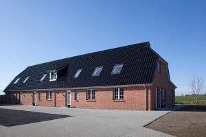 a large red brick building with a black roof at Ferienhaus Brise in Boren