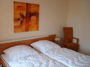 ein Schlafzimmer mit einem weißen Bett und einem Gemälde an der Wand in der Unterkunft Residenz Leuchtturm L15 in Rerik