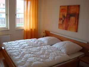 ein weißes Bett in einem Schlafzimmer mit einem Fenster in der Unterkunft Residenz Leuchtturm L15 in Rerik