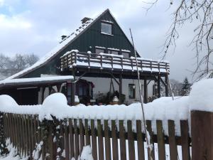 une maison verte avec une clôture dans la neige dans l'établissement Alpakahof Blomberg, à Meinerzhagen