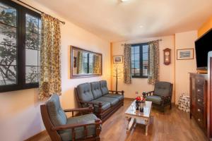 Una sala de estar con un sofá y sillas y ventanas. en Villa Doramas, en Firgas