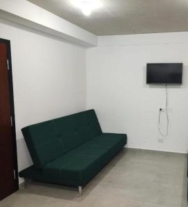 een groene bank in een kamer met een flatscreen-tv bij La Plaza MONOAMBIENTE in Sunchales