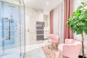a bathroom with two pink chairs and a glass table at Suite Hammam Love Luxe paisible in Les Pavillons-sous-Bois
