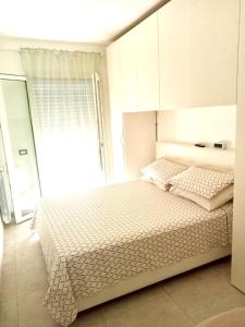 a white bedroom with a bed and a window at Alloggio by the sea in Focene +26 photos