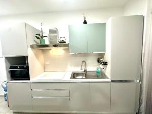 a kitchen with white cabinets and a sink at Alloggio by the sea in Focene