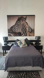 a bed with a picture of a zebra on the wall at Gemsbokrus in Marloth Park