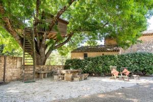 a patio with a tree with chairs and a ladder at Cabane Perchée avec Jacuzzi, au Coeur du Luberon in Oppède