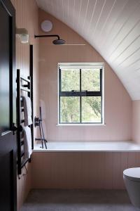 a bathroom with a window and a bath tub at Converted Nissen Barn on beautiful farm in Braintree