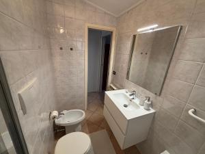 a white bathroom with a sink and a toilet at La Mansardina in Chioggia