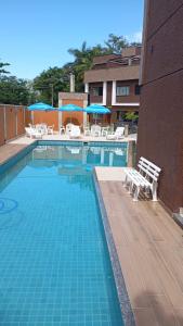 ein Swimmingpool mit Stühlen und Sonnenschirmen neben einem Gebäude in der Unterkunft Casa 01 Praia de Paúba-Maresias in Pauba