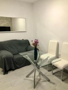 a living room with a glass table and two white chairs at La Casilla del Molino in Almodóvar del Río