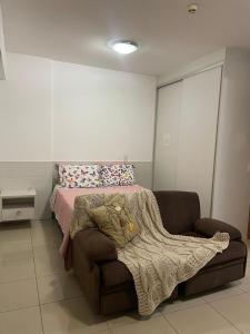 a bedroom with a bed and a couch with a blanket at Top Flat confortavel e muito bem localizado in Brasília