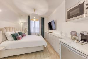 a white bedroom with a bed and a kitchen at Suite Love Hammam et Sauna in Les Pavillons-sous-Bois