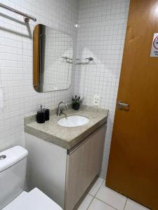 a bathroom with a sink and a mirror and a toilet at Top Flat confortavel e muito bem localizado in Brasília