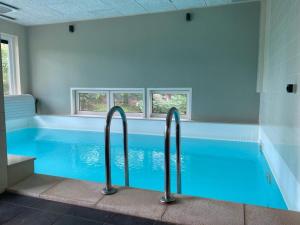 a blue swimming pool with three windows in a room at Bosch (10p) in Buren