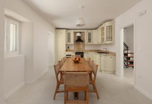 a white kitchen with a wooden table and chairs at Villa Magic Stone in Šišići