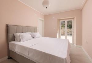 a white bedroom with a large bed with white sheets at Villa Magic Stone in Šišići +15 photos