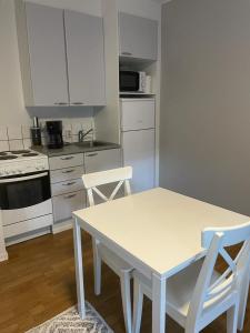 a white kitchen with a white table and chairs at Matkaparkki in Nokia