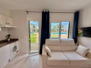 a living room with a white couch and a window at Apartamento con piscina - Posta de sol in Cala en Forcat