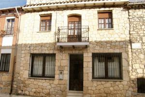 a stone building with windows and a balcony on it at Warm House in Baños de Valdearados, Farm Close to Town in Baños de Valdearados