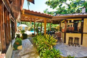 an outdoor patio with bar and stools next to a building at Pousada Estalagem Casa Grande in Ubatuba