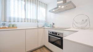 a white kitchen with a sink and a stove at Jardín de Doctrinos by Toledo AP in Toledo +19 photos