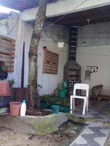 a patio with a tree and a chair and a fireplace at Aconchegante e familiar in Marituba