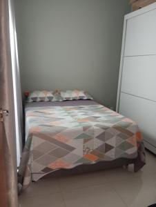 a bed with a quilt on it in a room at Casa Completa in Cascavel