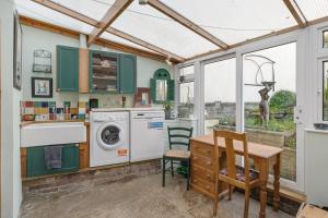 eine Küche mit grünen Schränken und einem Tisch mit einer Waschmaschine in der Unterkunft 17th Century Cottage in Bideford Private Parking in Bideford + 19 Fotos