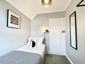 a small bedroom with a bed and a mirror at Large 4-bedroom detached house - Driveway for 3 cars - 20-minute walk to city centre - Gigabit Wi-Fi - Long Stay Rates! in Gloucester +39 photos