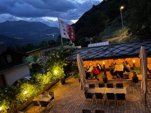 a group of people sitting at a restaurant at night at Long & Short Stay Hotel Bahnhof Ausserberg in Ausserberg