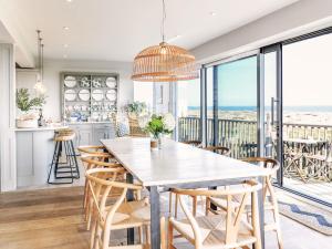 Una cocina y un comedor con mesa y sillas. en Spinneys Beachfront by The Suffolk Cottage Collection, en Thorpeness