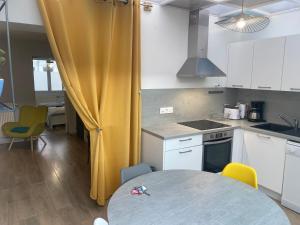 a kitchen with a table and a yellow curtain at L'Angelus d 'Etaples in Étaples