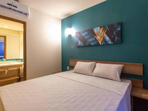 a bedroom with a white bed with a blue wall at Apartamento Enjoy Solar das Águas Park Resort in Olímpia