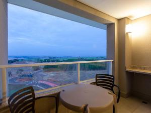 a room with a table and chairs and a large window at Apartamento Enjoy Solar das Águas Park Resort in Olímpia