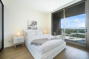悉尼Olympic Park Stylish Apt with Gym Pool good view的卧室里有一张白色的床和一扇大窗户