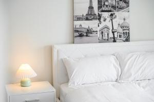 悉尼Olympic Park Stylish Apt with Gym Pool good view的一间卧室配有一张白色的床,床头灯上放着一盏灯 更多14张照片