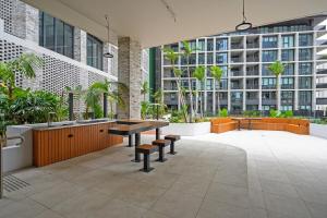悉尼Olympic Park Stylish Apt with Gym Pool good view的庭院设有桌子、长椅和建筑