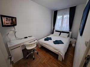 a bedroom with a bed and a desk and a computer at Plavi Paun Apartman in Belgrade