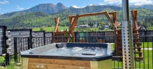 a hot tub on a balcony with mountains in the background at Good Morning Giewont & JACUZZI in Kościelisko