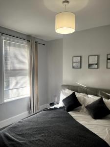 a bedroom with a large bed with a window at Cosy 2-Bed Home - Central Location Near Town & Train Station in Dartford