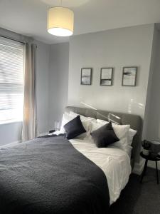 a bedroom with a bed with black and white pillows at Cosy 2-Bed Home - Central Location Near Town & Train Station in Dartford
