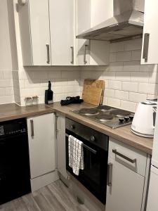 a kitchen with white cabinets and a stove top oven at Cosy 2-Bed Home - Central Location Near Town & Train Station in Dartford