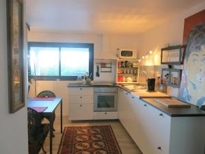 une cuisine avec des placards blancs, une table et une fenêtre dans l'établissement Appartement tout confort refait à neuf, à Deauville