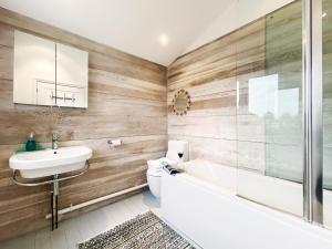 a bathroom with a sink and a tub and a toilet at Spinney's Boathouse by The Suffolk Cottage Collection in Thorpeness